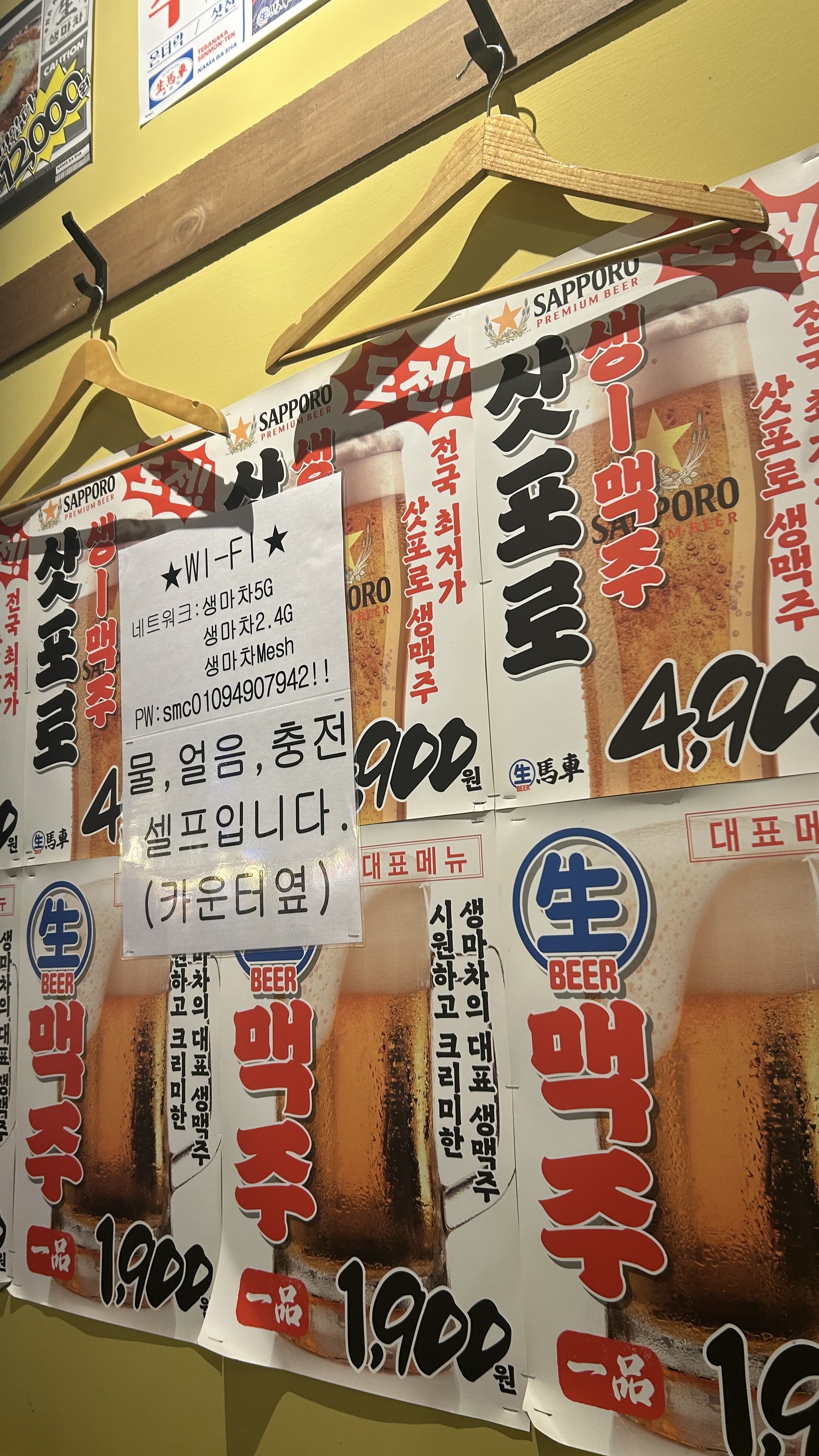 벽에 붙은 생맥주 가격 포스터와 와이파이 비밀번호 안내문