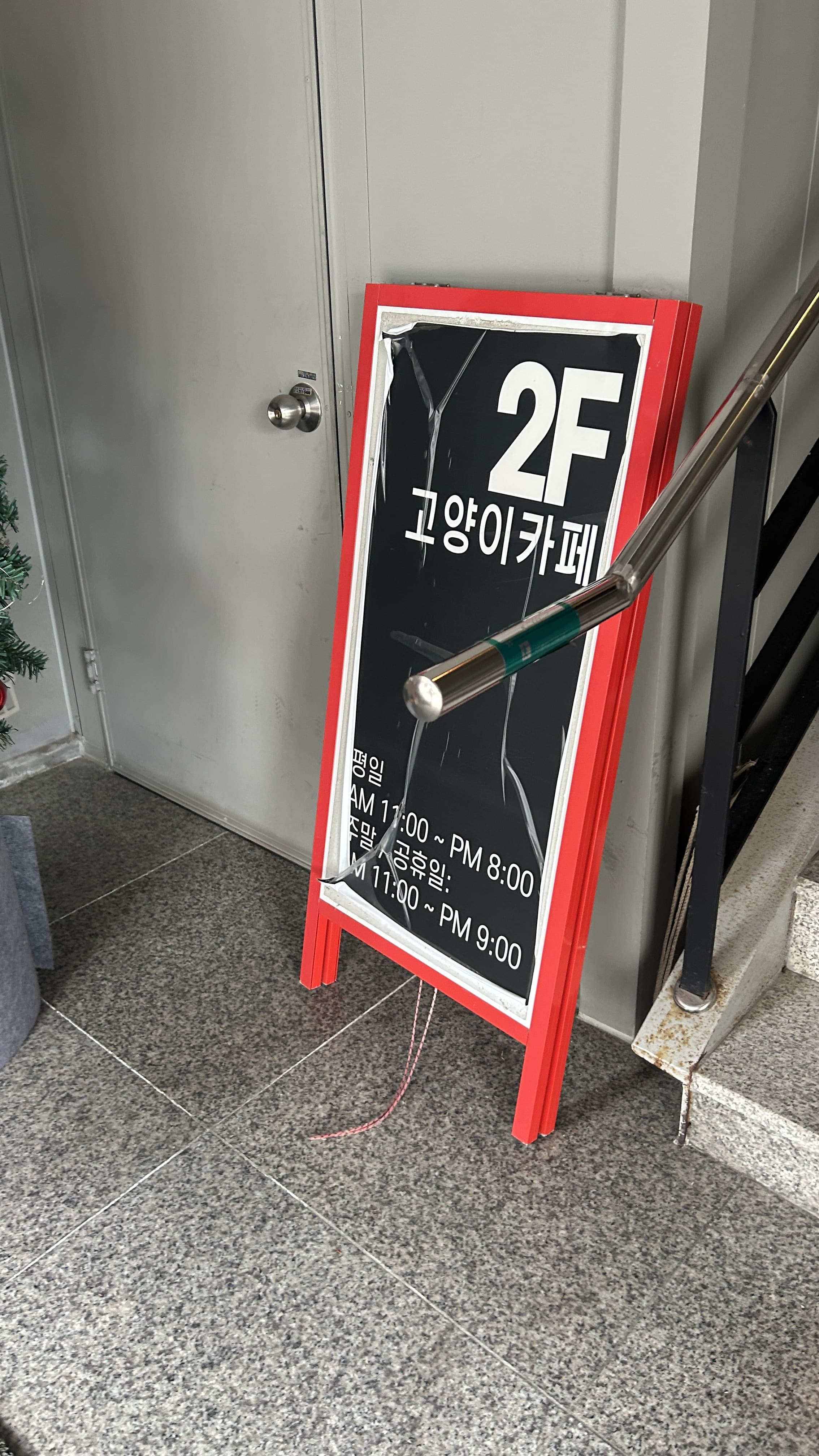 건물 입구 계단 옆에 세워진 2층 고양이카페 입간판